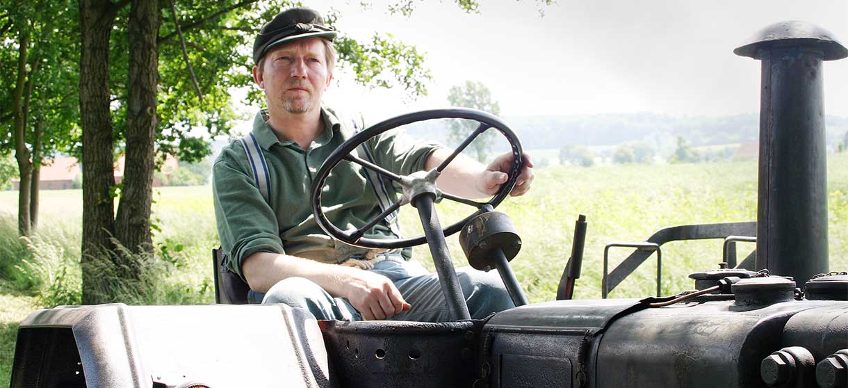 Niedersachsens Kult-Comedy: Günther sitzt auf einem Trecker auf einem grünen Feld