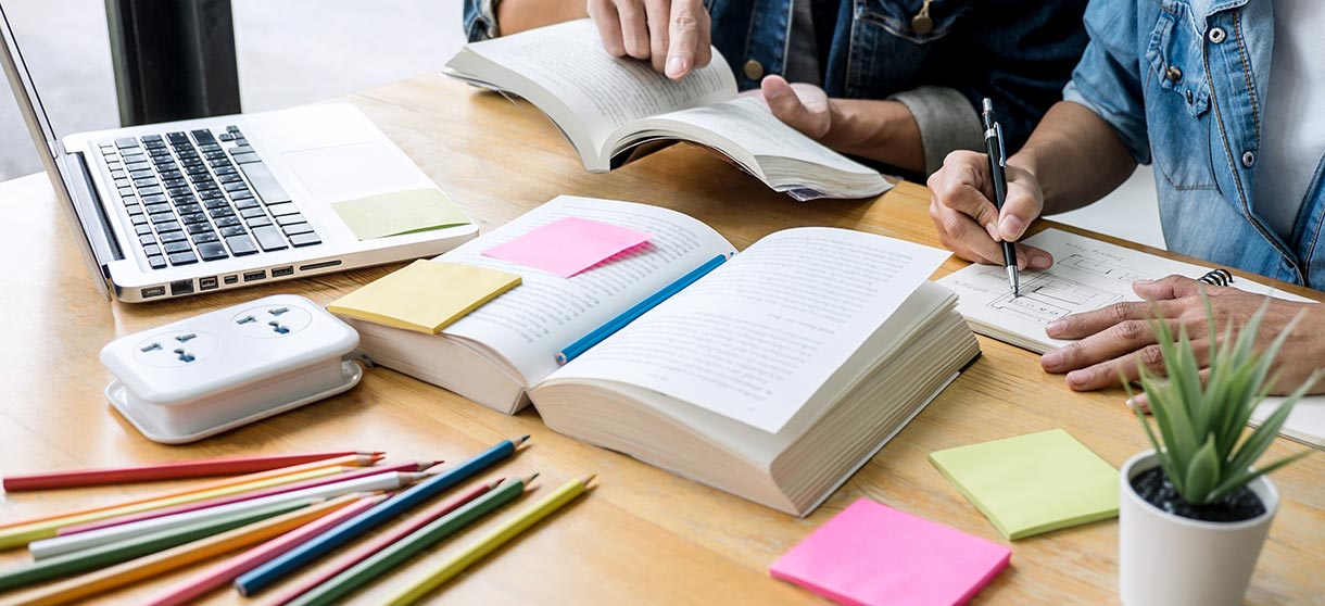 Ausbildungsbörse für Niedersachsen: zwei Studenten vor aufgeschlagenen Büchern und Rechner