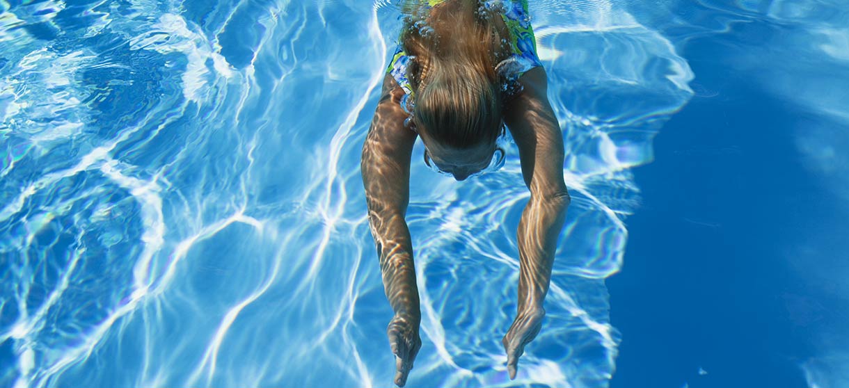 Kind schaut über den Rand im Schwimmbad