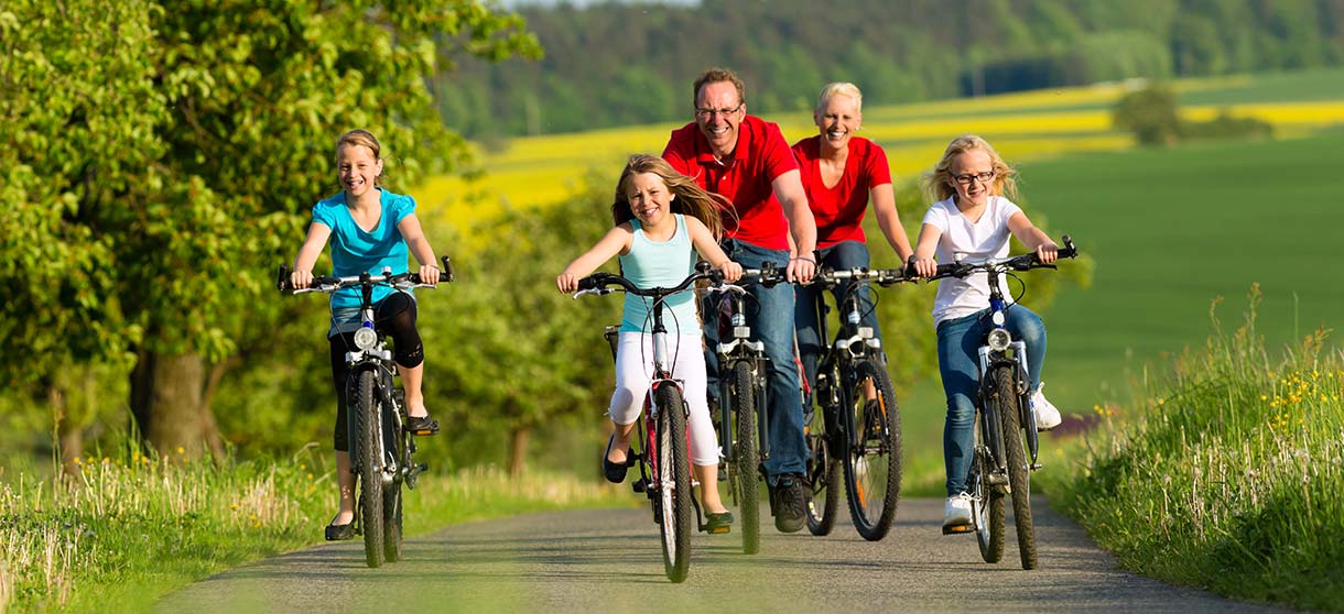 Freizeithighlights: Mann, Frau und drei Kinder auf Fahrrädern. die auf einem Feldweg fahren